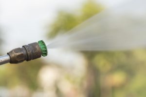 Pressure washing a vinyl fence.